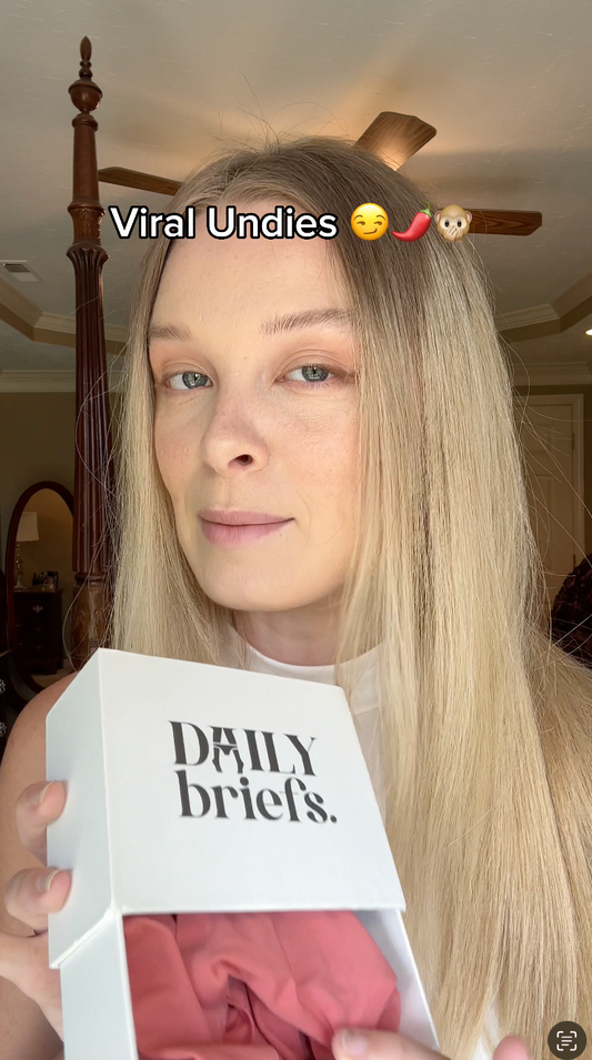 Person holding a box of 'Daily briefs' with text overlay 'Viral Undies' and emojis.