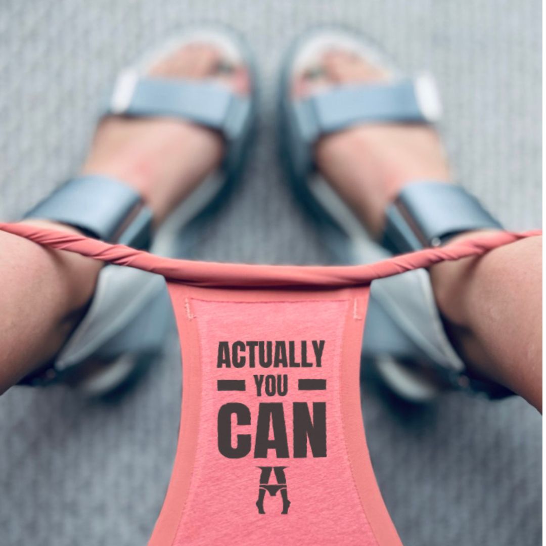 close-up lifestyle shot of a womans wearing 'ACTUALLY YOU CAN underwear The person is wearing gray slide sandals on a gray textured pavement background.