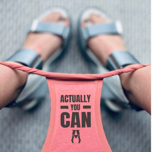 close-up lifestyle shot of a womans wearing 'ACTUALLY YOU CAN underwear The person is wearing gray slide sandals on a gray textured pavement background.