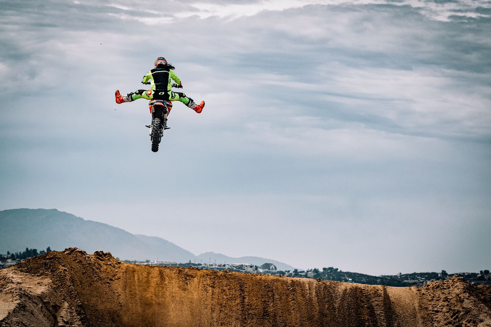 Fierce woman on a motorcycle performing a jump against a cloudy sky wearing Daily Briefs